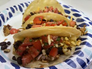 Tacos filled with shredded mushroom and baked tofu and topped with cheese and salsa