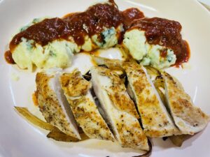 Pan fried chicken breast sliced with gnudi topped with marinara in the background
