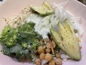 Salad topped with onion, brocolini, garbanzo beans, and avocado